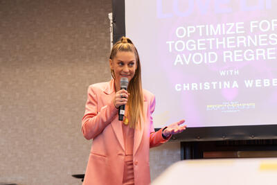 Christina Weber mid-gesture explaining a concept on stage at Beyond Biohacking Conference