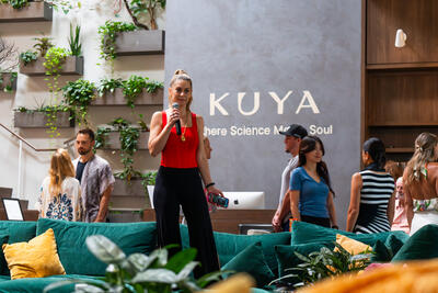 Christina Weber standing with microphone on stage at KUYA Wellness during Day of Biohacking Love