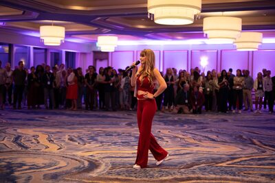 Christina Weber in red jumpsuit walking through the ballroom crowd at Beyond Biohacking Conference