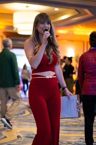 Christina Weber emceeing with microphone through the ballroom at Beyond Biohacking Conference