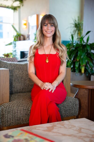 Christina Weber seated portrait in a red dress with gold pendant
